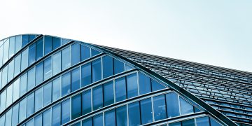 Sleek modern architecture with curved glass facade in an urban setting.