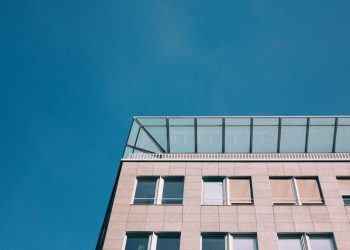 A modern building with glass windows set against a bright blue sky, showcasing contemporary architecture.