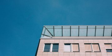 A modern building with glass windows set against a bright blue sky, showcasing contemporary architecture.