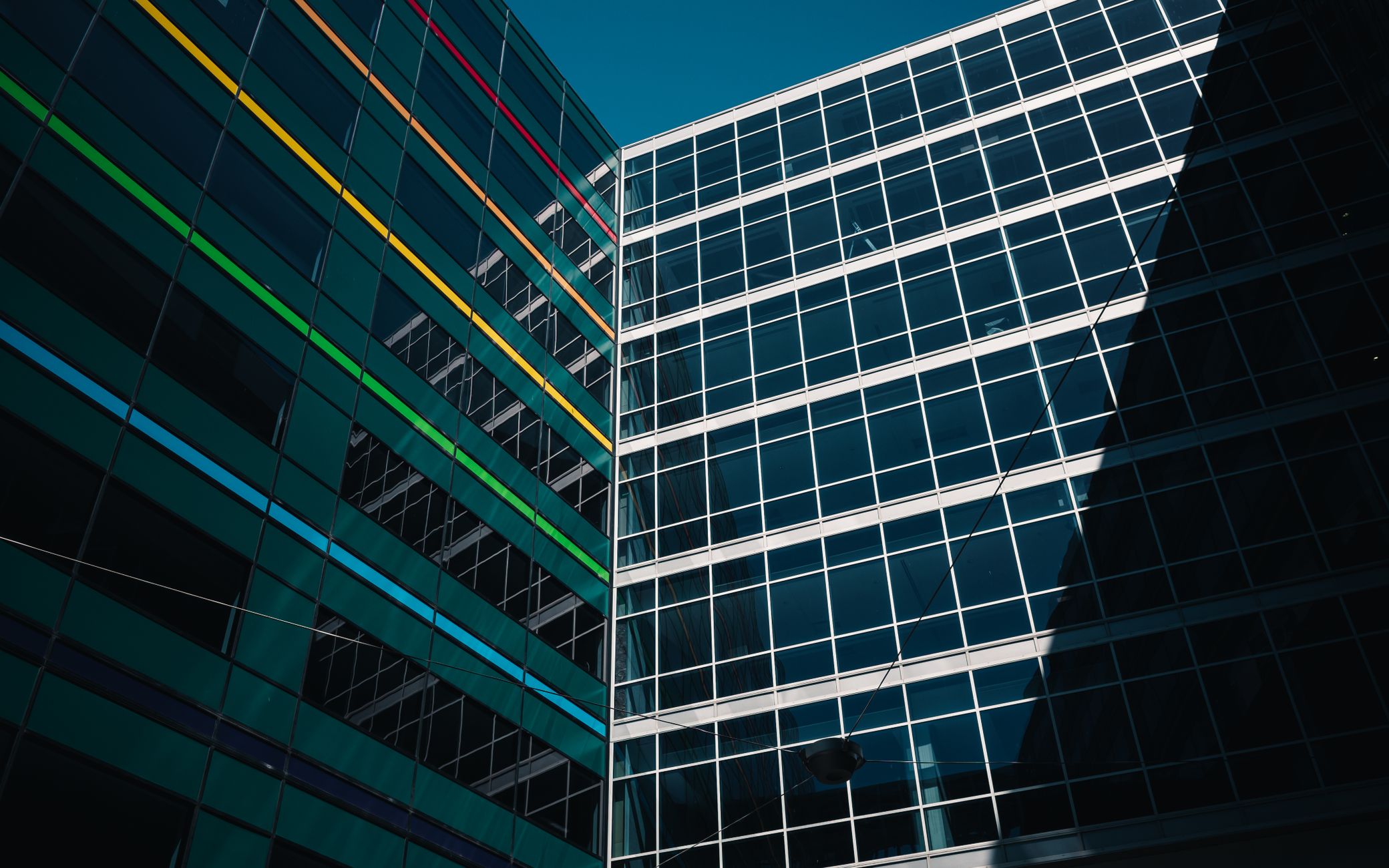 Architectural view of modern buildings with colorful stripes against a clear blue sky.