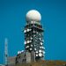 Imposing satellite tower with numerous dishes against a vibrant blue sky.