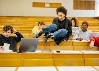 Diverse students interact and study in a university lecture hall.