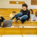 Diverse students interact and study in a university lecture hall.