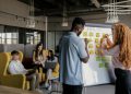 Team collaborating in a modern office, planning strategy on a whiteboard, young adults working together.
