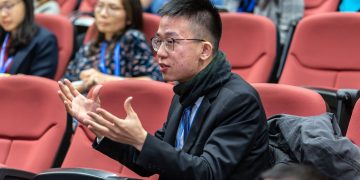 Students actively participating in a university lecture, discussing and engaging.