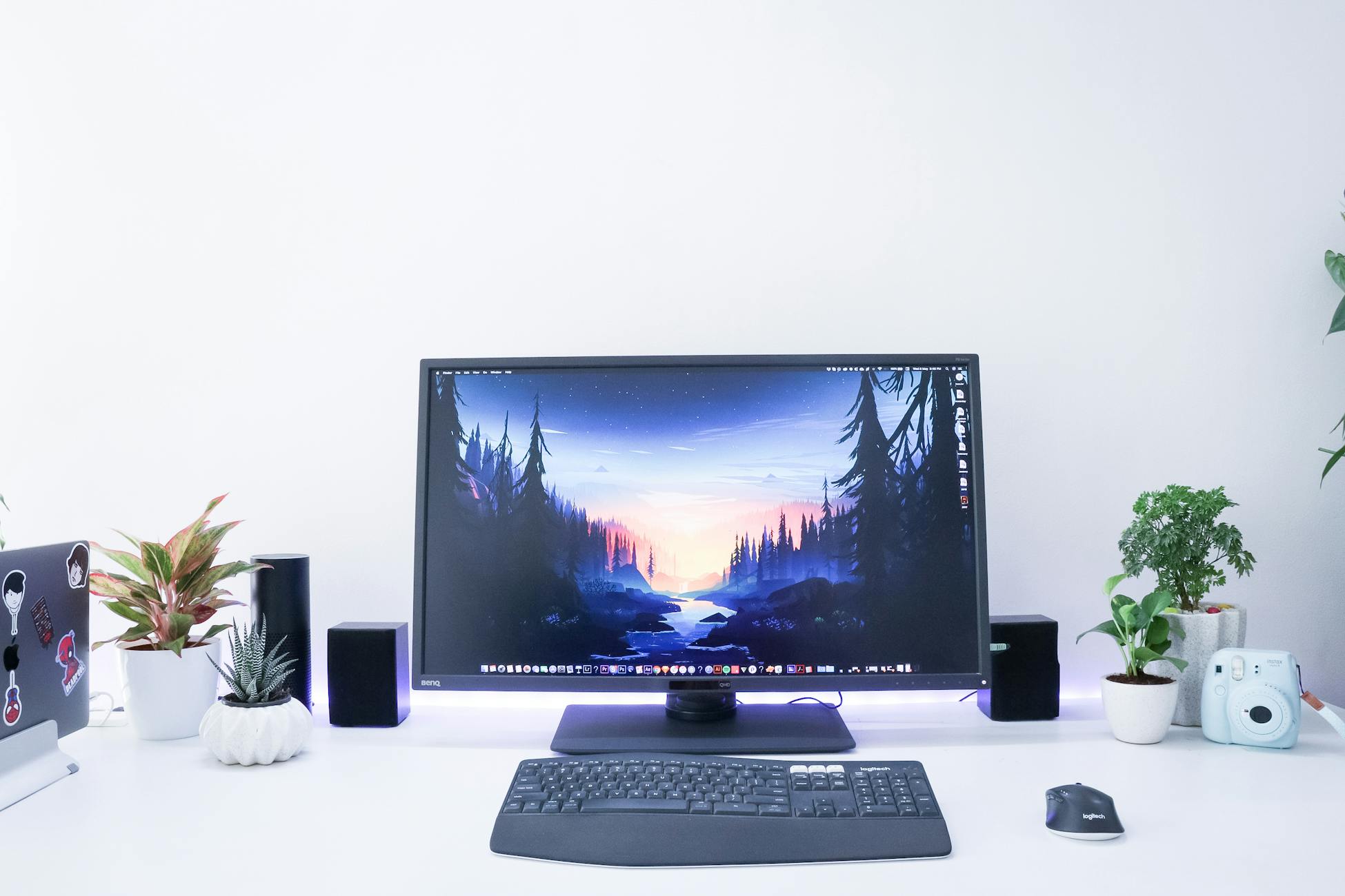 Contemporary desk setup featuring a monitor, plants, and electronic devices in a sleek, minimalist design.