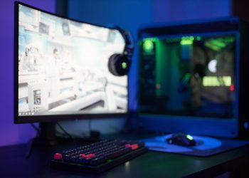 High-tech gaming setup featuring a curved monitor, RGB keyboard, and vibrant lighting.