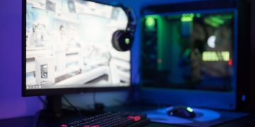 High-tech gaming setup featuring a curved monitor, RGB keyboard, and vibrant lighting.