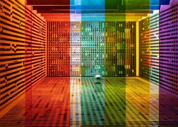 A vibrant, rainbow-themed room featuring patterned walls and colored glass panels creating a kaleidoscopic effect.