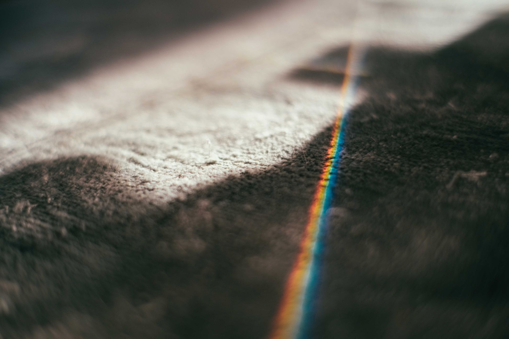 Gray old fashioned textured carpet with sunbeam of rainbow lights shining in light room with shadow and sunshine at home