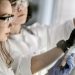 Two scientists in protective gear conducting a chemical experiment in a laboratory.