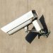 Close-up of a white security camera mounted on a beige wall in sunlight, emphasizing safety.