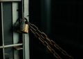 An artistic close-up photo of a faded padlock securing a chain on a metal door, symbolizing security.