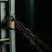 An artistic close-up photo of a faded padlock securing a chain on a metal door, symbolizing security.