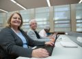 Smiling seniors learning computer skills in a modern classroom setting.
