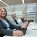 Smiling seniors learning computer skills in a modern classroom setting.