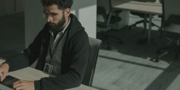 Bearded man working on a computer indoors, focused on cybersecurity tasks.