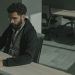 Bearded man working on a computer indoors, focused on cybersecurity tasks.