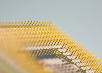 Detailed close-up of gold CPU pins, showcasing technology and design on a circuit board.