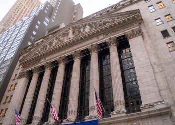Close-up view of the iconic New York Stock Exchange building with American flags, located in Wall Street, NYC.