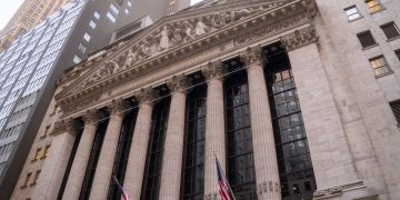 Close-up view of the iconic New York Stock Exchange building with American flags, located in Wall Street, NYC.