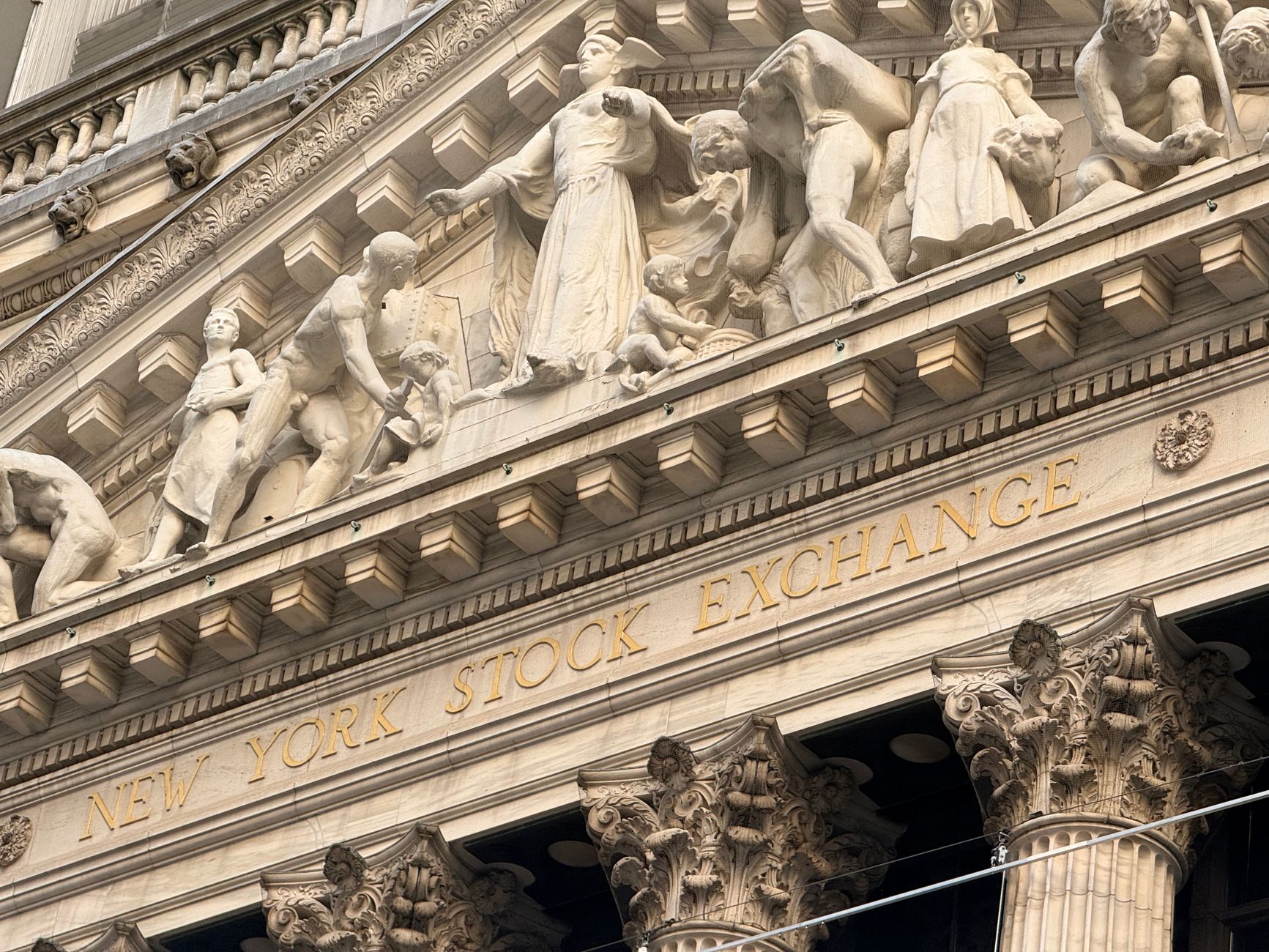 Ornate façade of the New York Stock Exchange featuring intricate stone sculptures during daylight.