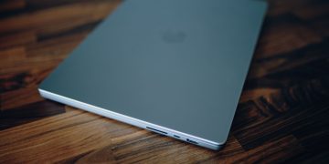 Closed laptop on a polished wooden table, emphasizing clean design and technology.