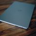 Closed laptop on a polished wooden table, emphasizing clean design and technology.
