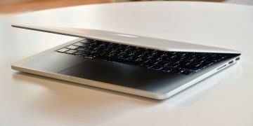 A modern MacBook laptop with a sleek design, slightly closed on a white table indoors.