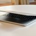 A modern MacBook laptop with a sleek design, slightly closed on a white table indoors.