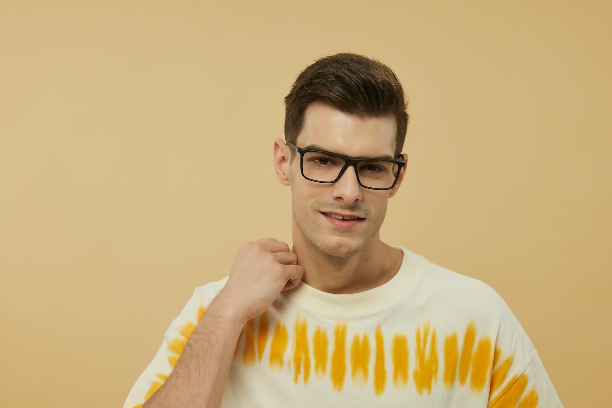 Confident man posing with fashionable eyewear against a warm background.
