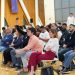 A diverse audience attentively listens during an indoor seminar, showcasing a collaborative learning environment.