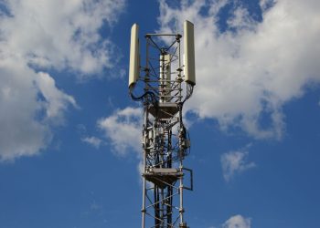 A tall cellular communication tower against a vivid blue sky, symbolizing modern technology.