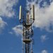 A tall cellular communication tower against a vivid blue sky, symbolizing modern technology.