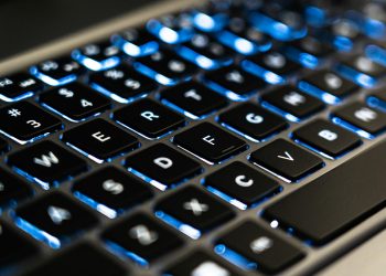 Detailed view of a backlit laptop keyboard keys with blue LED lighting for tech concepts.