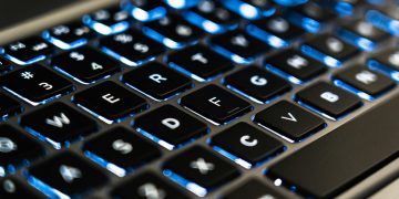 Detailed view of a backlit laptop keyboard keys with blue LED lighting for tech concepts.