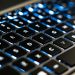 Detailed view of a backlit laptop keyboard keys with blue LED lighting for tech concepts.