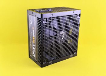 Black computer power supply unit with fan displayed against yellow background.
