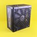 Black computer power supply unit with fan displayed against yellow background.