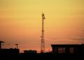 Urban landscape silhouette featuring a communication tower against a vibrant sunset sky.