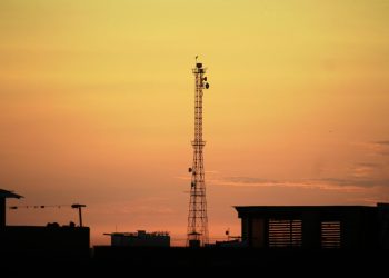 Urban landscape silhouette featuring a communication tower against a vibrant sunset sky.