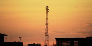Urban landscape silhouette featuring a communication tower against a vibrant sunset sky.