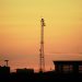 Urban landscape silhouette featuring a communication tower against a vibrant sunset sky.