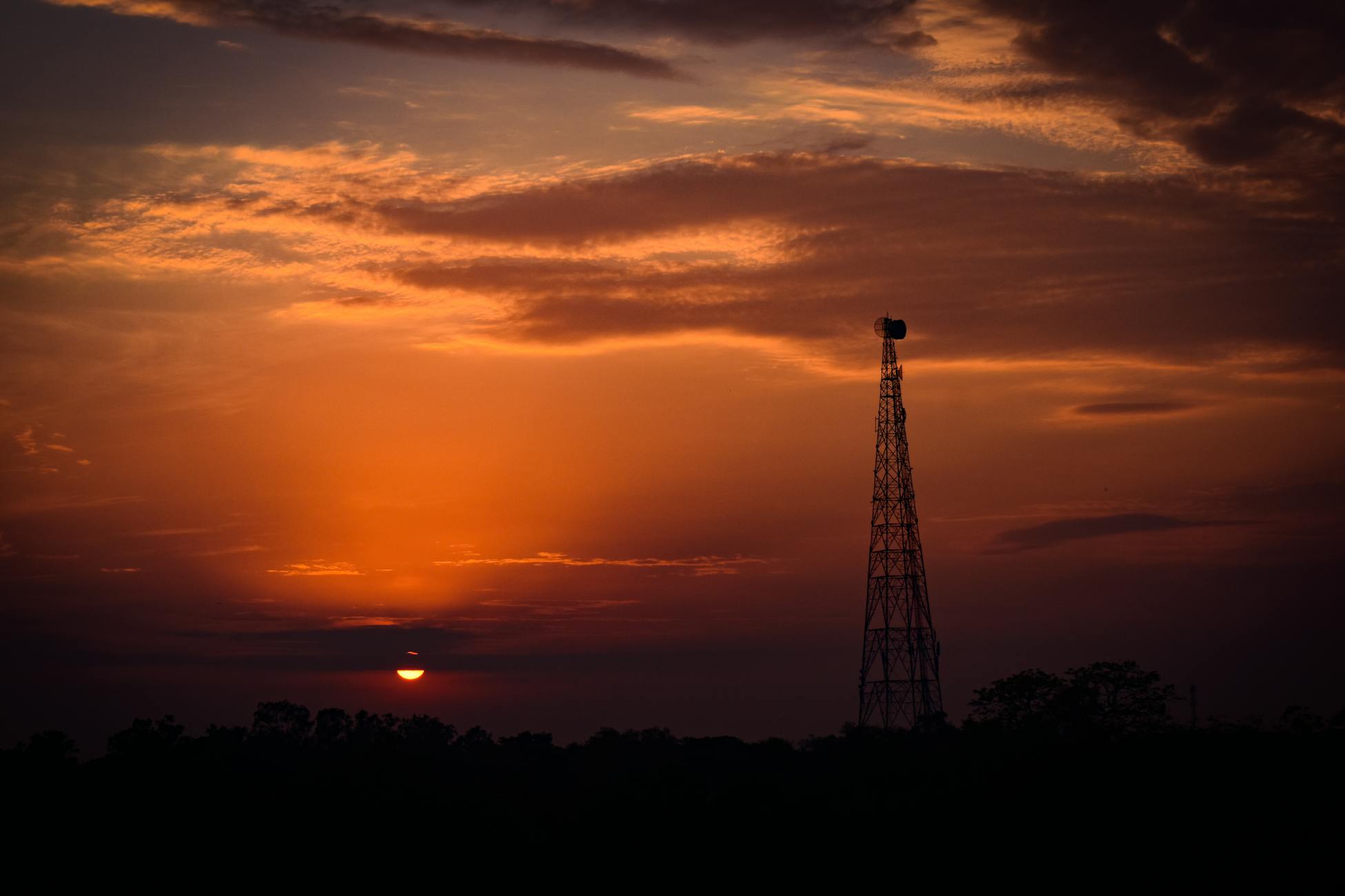 A striking sunset with a silhouetted telecom tower against vibrant skies.