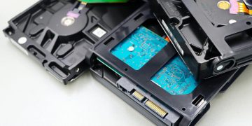 Stack of internal hard disk drives for digital storage on white background.