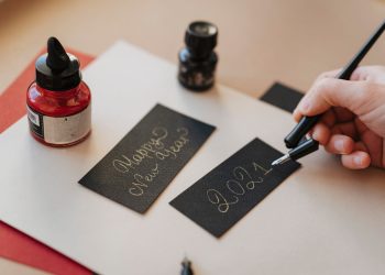 A hand writes 'Happy New Year 2021' in calligraphy with a fountain pen.
