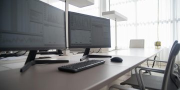 Stylish contemporary office featuring multiple computer monitors and ergonomic chairs.