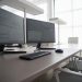 Stylish contemporary office featuring multiple computer monitors and ergonomic chairs.
