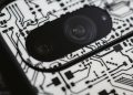 Macro shot of an electronic circuit design around a smartphone camera lens, showing intricate details.