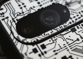 Macro shot of an electronic circuit design around a smartphone camera lens, showing intricate details.